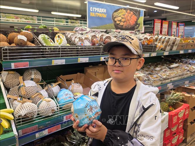 Một khách hàng châu Á với mặt hàng dừa có ống hút của Việt Nam. Ảnh: Trần Hải  - PV TTXVN tại Nga 