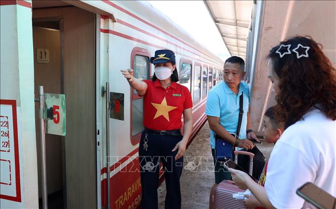 Nhân viên tàu hướng dẫn hành khách lên đúng toa, ngồi đúng số ghế trên toa. Ảnh: Quốc Khánh - TTXVN
