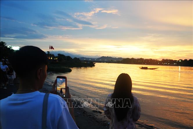 Giới trẻ chụp ảnh lưu lại cảnh đẹp của hoàng hôn từ bờ Nam sông Hương, thành phố Huế. Ảnh: Nguyên Lý - TTXVN