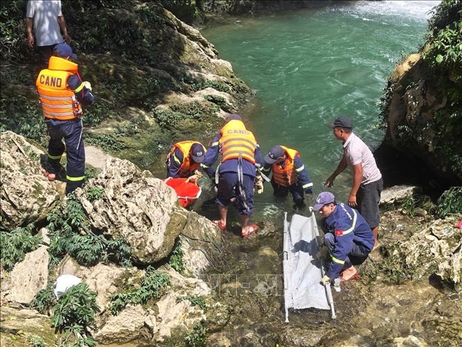 Lực lượng chức năng đưa thi thể nạn nhân qua địa hình đá trơn trượt. Ảnh: TTXVN phát