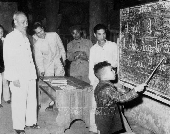 Chủ tịch Hồ Chí Minh quan sát một cháu thiếu nhi tập đánh vần khi đến thăm lớp vỡ lòng Đình Thạch Khối ở phố Hàng Than, Hà Nội (31/12/1958). Ảnh: TTXVN
