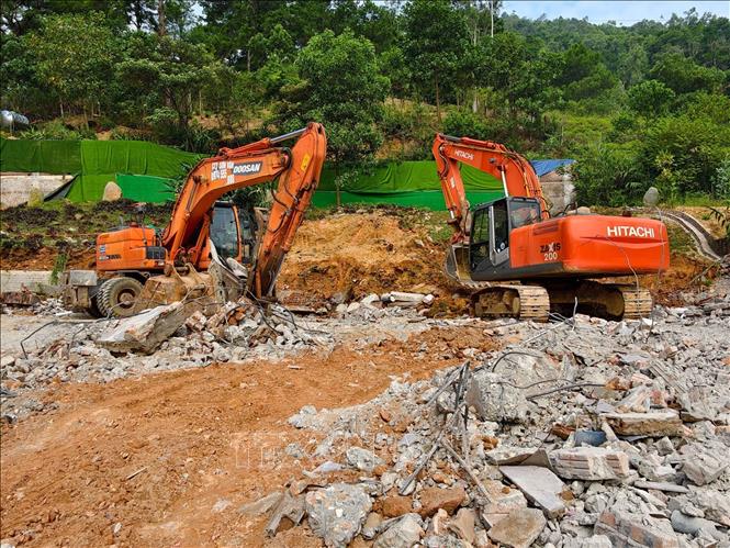 Máy xúc và xe tải được huy động vận chuyển phế thải trong quá trình cưỡng chế công trình vi phạm tại thôn Thái Vụ. Ảnh: Trung Nguyên - TTXVN