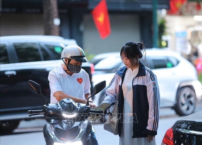 Nữ sinh lớp 10 Trường THPT Việt Đức được bố đưa đến trường từ sớm để dự Lễ khai giảng đầu tiên ở ngôi trường mới. Ảnh: Hoàng Hiếu - TTXVN 