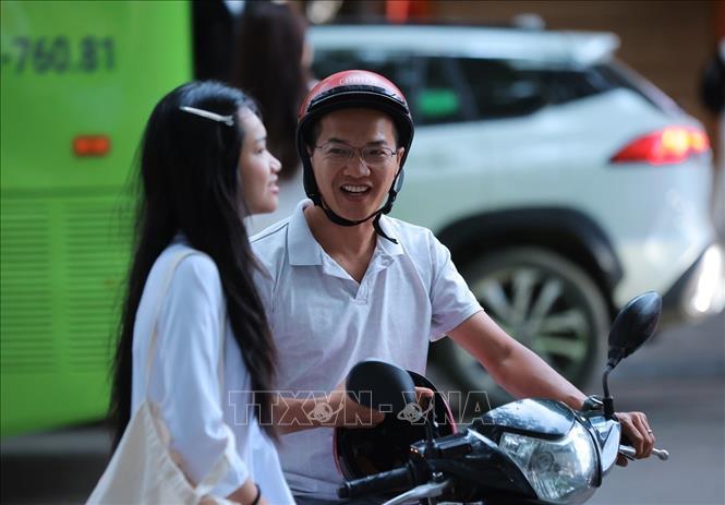 Nữ sinh lớp 10 Trường THPT Việt Đức được bố đưa đến trường từ sớm để dự Lễ khai giảng đầu tiên ở ngôi trường mới. Ảnh: Hoàng Hiếu - TTXVN 