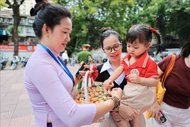Các em nhỏ vui vẻ nhận những viên kẹo từ thầy cô, cán bộ nhà trường trong ngày khai giảng tại Trường mầm non Kim Liên (Hà Nội). Ảnh: Lê Đông - TTXVN