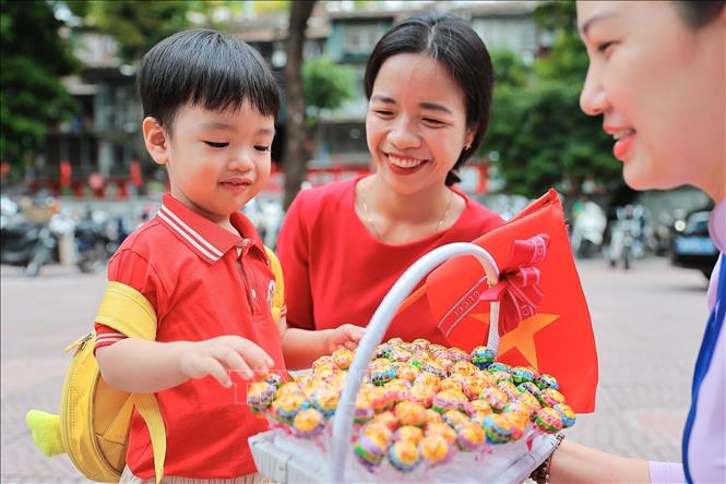 Các em nhỏ vui vẻ nhận những viên kẹo từ thầy cô, cán bộ nhà trường trong ngày khai giảng tại Trường mầm non Kim Liên (Hà Nội). Ảnh: Lê Đông - TTXVN