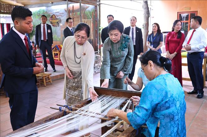 Phu nhân Ngô Phương Ly và Phu nhân Kyu Kyu Hla quan sát khung dệt và xem các nghệ nhân trình diễn dệt lụa. Ảnh: Minh Đức – TTXVN