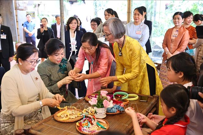 Phu nhân Ngô Phương Ly và Phu nhân Kyu Kyu Hla trải nghiệm xâu vòng lụa với các cháu thiếu niên, nhi đồng của làng nghề. Ảnh: Minh Đức – TTXVN