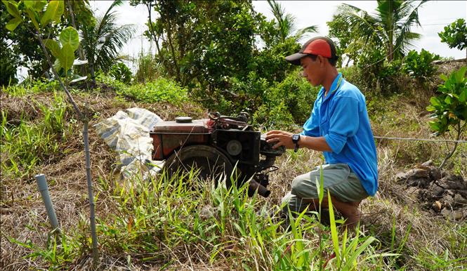 Anh Nguyễn Văn Toàn ở xã Mỹ Thiện (tỉnh Đồng Tháp) chuẩn bị sẵn máy bơm nước để bảo vệ vườn sầu riêng hơn 1 ha. Ảnh: Nhựt An - TTXVN