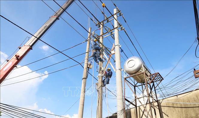 Xe cẩu và công nhân đơn vị thi công được huy động để thực hiện di dời hệ thống điện trên tuyến đường tỉnh 753, phục vụ dự án nâng cấp, mở rộng tuyến đường. Ảnh: Đậu Tất Thành – TTXVN
