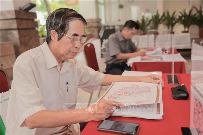 Nhiều người dân không chỉ góp ý kiến mà còn chụp từng hình ảnh, phương án để nghiên cứu. Ảnh: Phan Phương – TTXVN