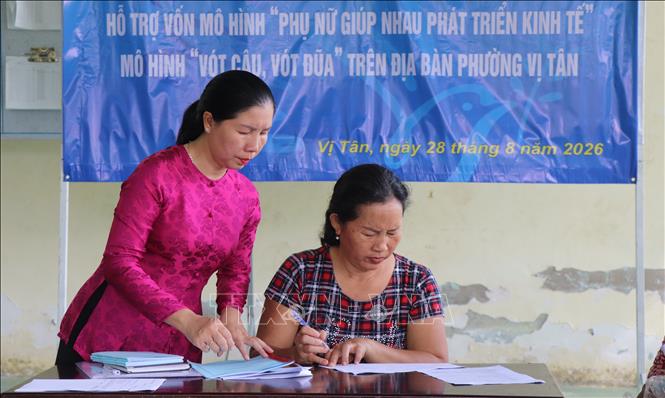 Chủ tịch Hội LHPN phường Vị Tân hỗ trợ hội viên đăng ký tham gia mô hình phát triển kinh tế. Ảnh: Nguyễn Hằng - TTXVN