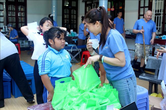 Các tình nguyện viên tư vấn, hướng dẫn trẻ hình thành thói quen vệ sinh răng miệng hằng ngày. Ảnh: Hồng Hiếu - TTXVN