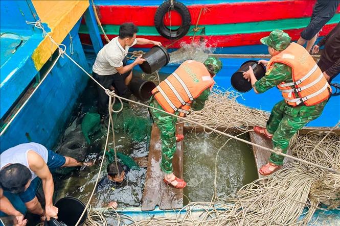 Lực lượng chức năng đã huy động máy bơm nước, trục vớt, đưa phương tiện lên vị trí an toàn. Ảnh: TTXVN phát 