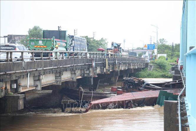 Do ảnh hưởng của mưa lớn và nước lũ dâng cao khiến 3 xà lan bị đứt dây neo trôi dạt và mắc kẹt tại khu vực cầu đường sắt Mỹ Chánh và cầu đường bộ Mỹ Chánh. Ảnh: TTXVN phát