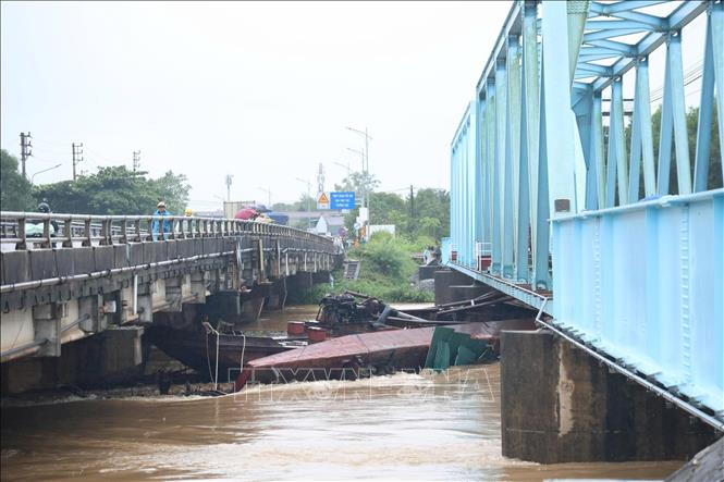 Do ảnh hưởng của mưa lớn và nước lũ dâng cao khiến 3 xà lan bị đứt dây neo trôi dạt và mắc kẹt tại khu vực cầu đường sắt Mỹ Chánh và cầu đường bộ Mỹ Chánh. Ảnh: TTXVN phát