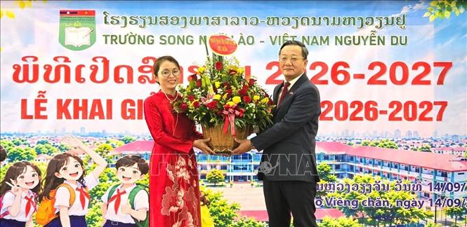 Đại sứ Việt Nam tại Lào Nguyễn Minh Tâm tặng hoa chúc mừng Ban Giám hiệu trường Song ngữ Lào - Việt Nam Nguyễn Du nhân dịp khai giảng năm học mới. Ảnh: Xuân Tú - PV TTXVN tại Lào