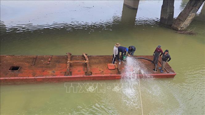 Lực lượng cứu hộ bơm nước trong khoang, kết hợp cần cẩu loại lớn kéo nổi sà lan. Ảnh: Nguyên Linh - TTXVN