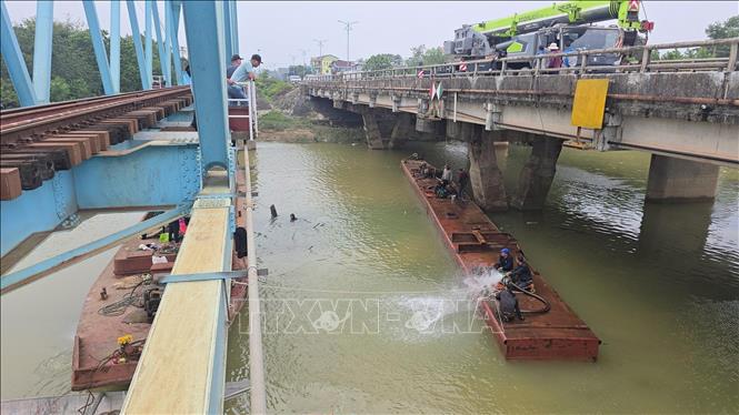 Lực lượng cứu hộ bơm nước trong khoang, kết hợp cần cẩu loại lớn kéo nổi sà lan. Ảnh: Nguyên Linh - TTXVN