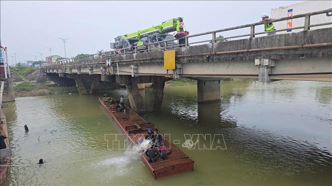 Sà lan bị chìm tại chân cầu Mỹ Chánh được lực lượng cứu hộ dùng cần cẩu kéo nổi, trục vớt an toàn. Ảnh: Nguyên Linh - TTXVN