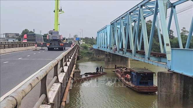 Sà lan bị chìm tại chân cầu Mỹ Chánh được lực lượng cứu hộ dùng cần cẩu kéo nổi, trục vớt an toàn. Ảnh: Nguyên Linh - TTXVN