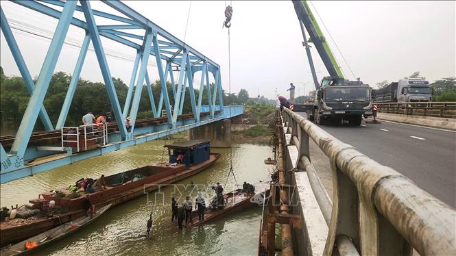 Lực lượng chức năng sử dụng cần cẩu loại lớn để trục vớt sà lan bị chìm tại chân cầu Mỹ Chánh. Ảnh: Nguyên Linh - TTXVN
