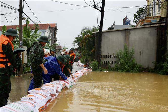 Lực lượng bộ đội hỗ trợ đắp đê bao ngăn nước khu dân cư ven sông Bùi. Ảnh: Nhật Anh - TTXVN