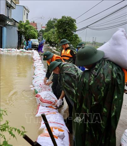 Lực lượng bộ đội hỗ trợ đắp đê bao ngăn nước khu dân cư ven sông Bùi. Ảnh: Nhật Anh - TTXVN