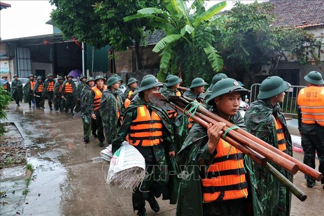 Cán bộ, chiến sĩ Trung đoàn 102, Sư đoàn 308 mang theo bao vật liệu, chuẩn bị đắp đê ngăn nước lũ tại xã Quảng Bị. Ảnh: Phạm Tuấn Anh - TTXVN