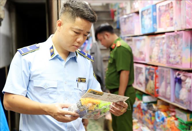 Lực lượng chức năng kiểm tra đồ chơi trẻ em tại cửa hàng số 3B Đồng Xuân. Ảnh: Trần Việt - TTXVN