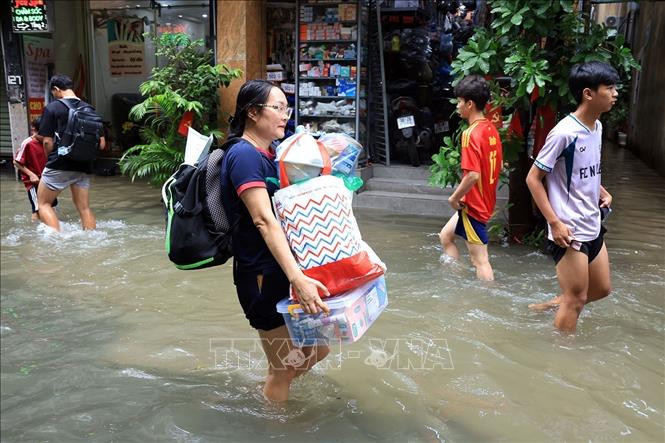 Người dân di chuyển đồ đạc đến nơi khô ráo. Ảnh: Tuấn Anh - TTXVN