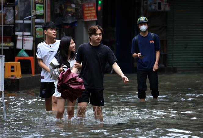 Người dân đi lại khó khăn do nước ngập sâu trên phố Triều Khúc, phường Thanh Liệt. Ảnh: Tuấn Anh - TTXVN