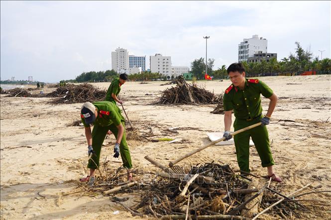Lực lượng chức năng khẩn trương dọn rác, làm sạch bãi biển Nhật Lệ sau mưa lũ. Ảnh: Thanh Thuỷ-TTXVN                                                              