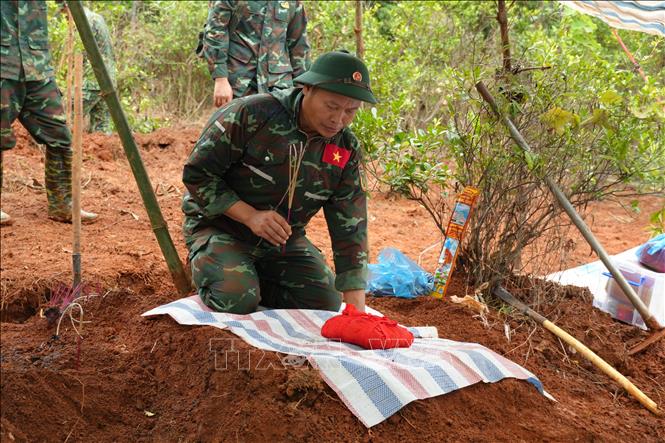 Thắp hương trước khi đưa hài cốt liệt sĩ về khu vực tập trung. Ảnh: Hồng Ninh - TTXVN