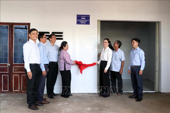 Lãnh đạo thành phố Cần Thơ và chính quyền địa phương thực hiện tháo khăn, gắn biển bàn giao nhà mới cho gia đình bà Võ Thị Liến. Ảnh: Trung Kiên - TTXVN