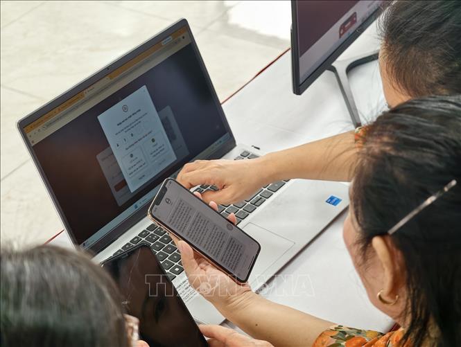 Thành viên Tổ chuyển đổi số cộng đồng hướng dẫn người dân tiếp cận, sử dụng các tiện ích số. Ảnh: Trung Nguyên - TTXVN