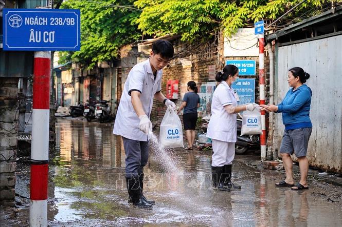 Cán bộ y tế phường Hồng Hà tham gia vệ sinh môi trường cùng người dân. Ảnh: Kim Anh - TTXVN