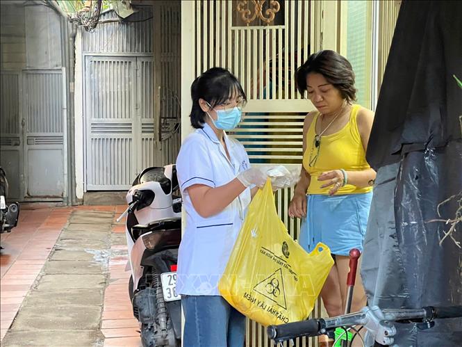 Cán bộ y tế phát cloraminB và hướng dẫn người dân cách sử dụng.
Ảnh: Kim Anh - TTXVN