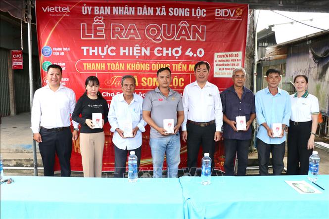 Lãnh đạo địa phương và các đơn vị đồng hành trao bảng mã QR và loa thông báo cho các tiểu thương tại lễ ra quân. Ảnh: Thanh Hòa - TTXVN