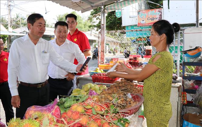 Lãnh đạo UBND xã Song Lộc tuyên truyền, hướng dẫn tiểu thương  sử dụng phương thức thanh toán không dùng tiền mặt. Ảnh: Thanh Hòa - TTXVN