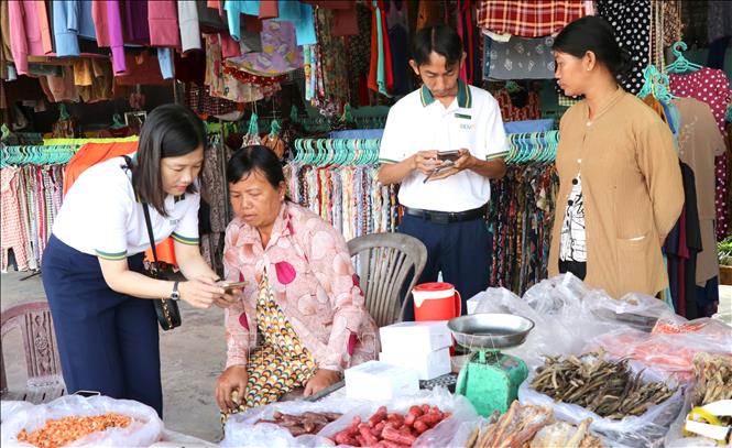 Hỗ trợ tiểu thương chợ Cầu Xây tại tài khoản ngân hàng và hướng dẫn sử dụng. Ảnh: Thanh Hòa - TTXVN