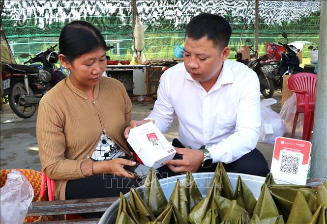 Đại diện Viettel trao và hướng dẫn tiểu thương chợ Cầu Xây sử dụng bảng mã QR. Ảnh: Thanh Hòa - TTXVN