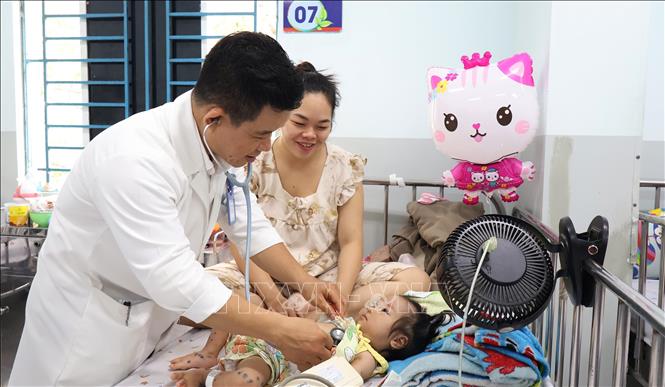 Bác sĩ Bệnh viện Nhi đồng 1 Thành phố Hồ Chí Minh đang thăm khám cho bệnh nhi mắc tay chân miệng. Ảnh: Đinh Hằng - TTXVN
