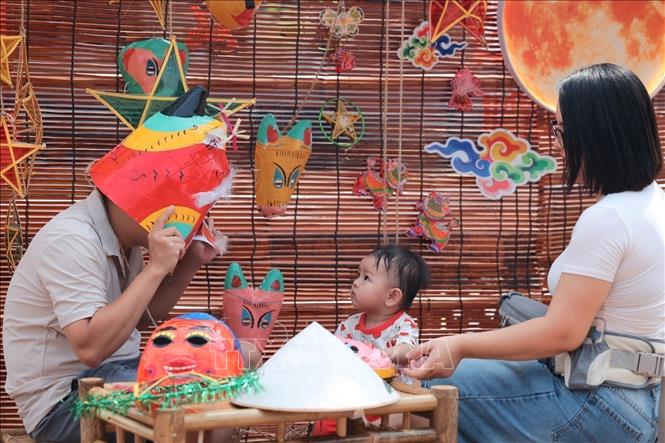 A child excitedly watches her father try on a paper-mache mask amidst the traditional Mid-Autumn toy display at the Ho Van space. VNA Photo: Phạm Tuấn Anh