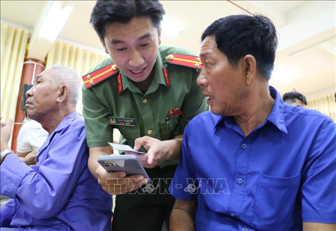  Cán bộ, chiến sĩ Công an tỉnh Đồng Tháp hỗ trợ người dân cài đặt các ứng dụng chuyển đổi số. Ảnh: Hồng Thái - TTXVN