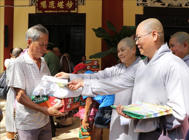 Chư ni hỗ trợ lực lượng công an Đồng Tháp phát tờ rơi tuyên truyền phòng, chống tội phạm cho bà con nhân dân. Ảnh: Hồng Thái - TTXVN