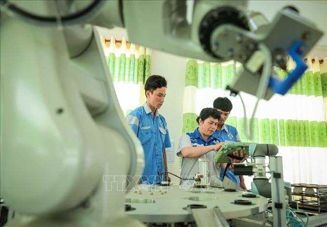 Thạc sĩ Phan Hoài Loan – Giảng viên khoa Điện tử đang hướng dẫn sinh viên nghề Kỹ thuật điều khiển và Tự động hóa vận hành cánh tay Robot. Ảnh: Hoàng Hiếu – TTXVN
