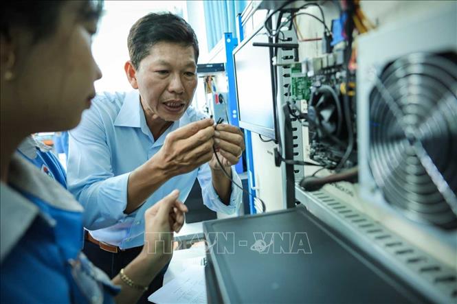 Thạc sĩ Đàm Quang Viễn - giảng viên khoa Công nghệ thông tin hướng dẫn sinh viên thực hành lắp ráp máy vi tính. Ảnh: Hoàng Hiếu – TTXVN