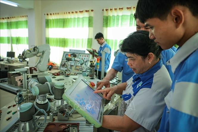 Thạc sĩ Phan Hoài Loan – Giảng viên khoa Điện tử đang hướng dẫn sinh viên nghề Kỹ thuật điều khiển và Tự động hóa vận hành cánh tay Robot. Ảnh: Hoàng Hiếu – TTXVN
