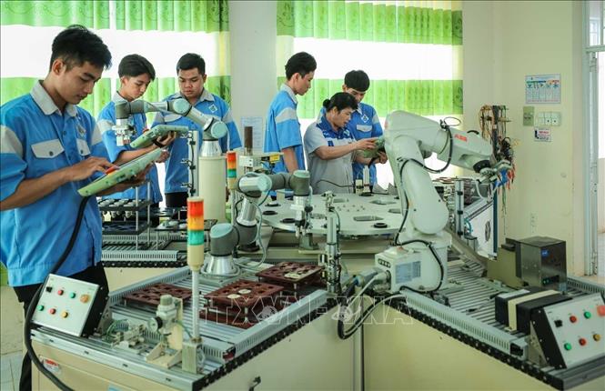 Thạc sĩ Phan Hoài Loan – Giảng viên khoa Điện tử đang hướng dẫn sinh viên nghề Kỹ thuật điều khiển và tự động hóa vận hành cánh tay Robot. Ảnh: Hoàng Hiếu – TTXVN